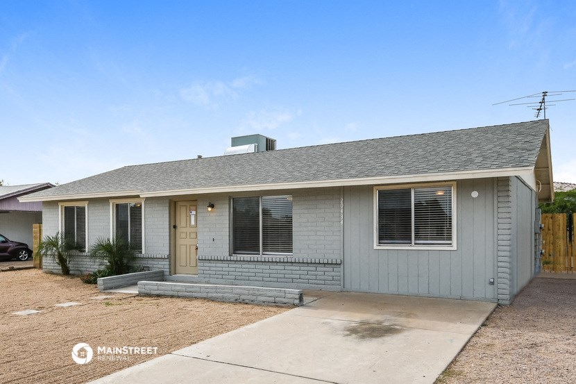 a small gray house with a porch and a wooden fence