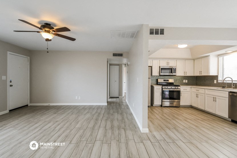 an empty kitchen with white cabinets and a ceiling fan