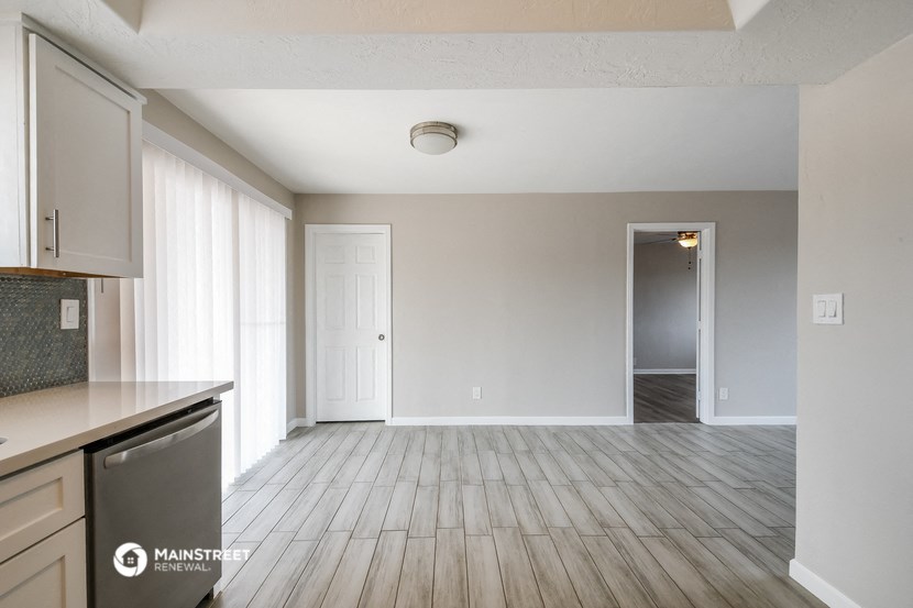 an empty kitchen and living room with wood floors and white walls