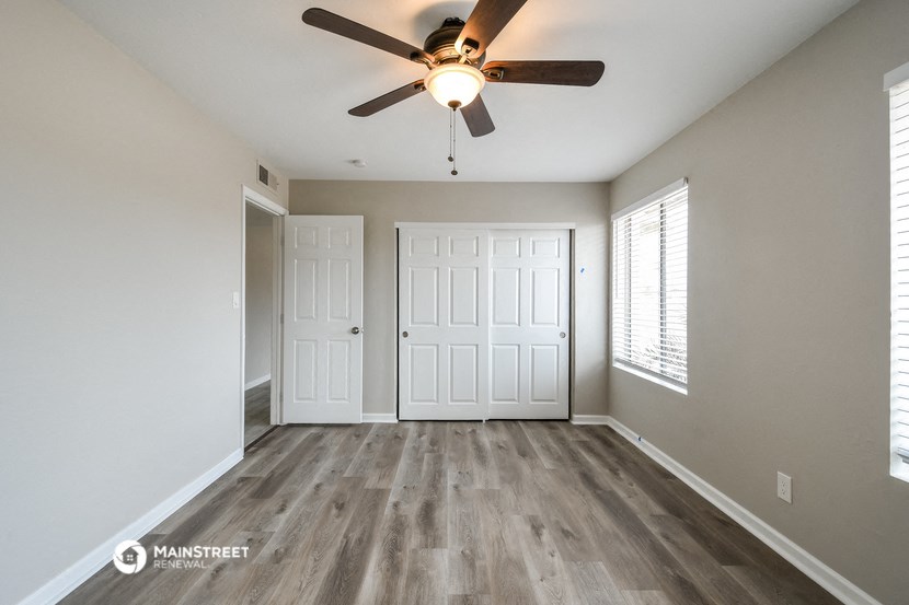the spacious living room with a ceiling fan and white doors