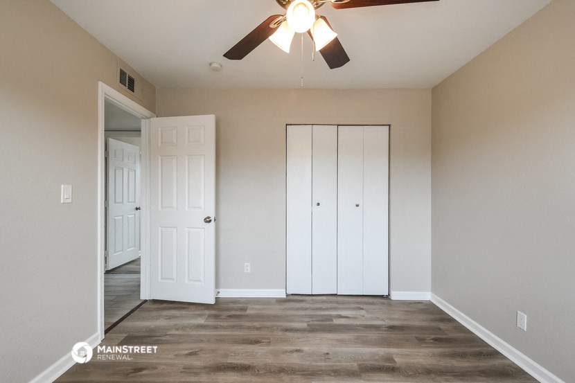 an empty living room with a ceiling fan and a closet
