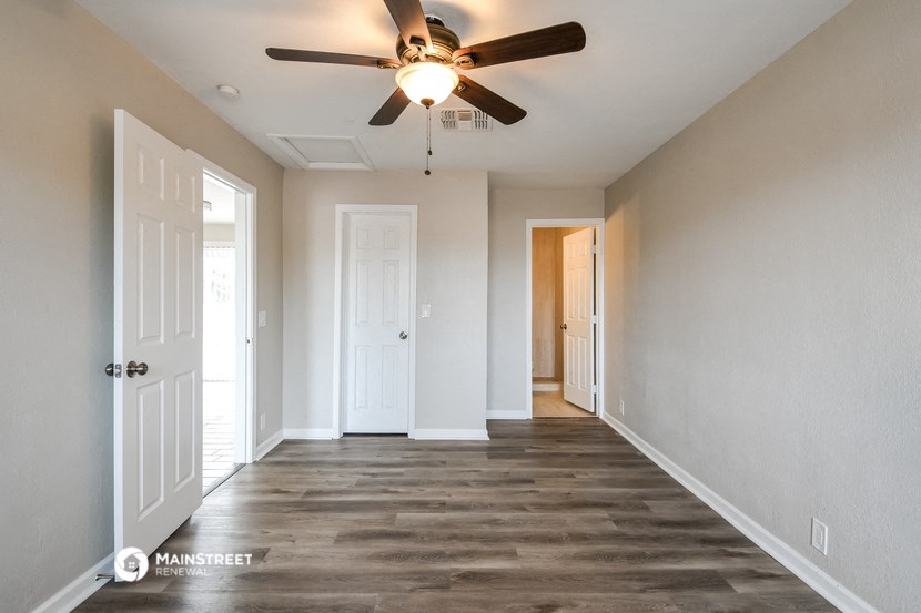 an empty hallway with a ceiling fan and a door to a closet
