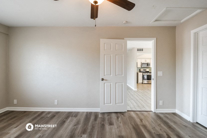 an empty living room with a white door and a ceiling fan