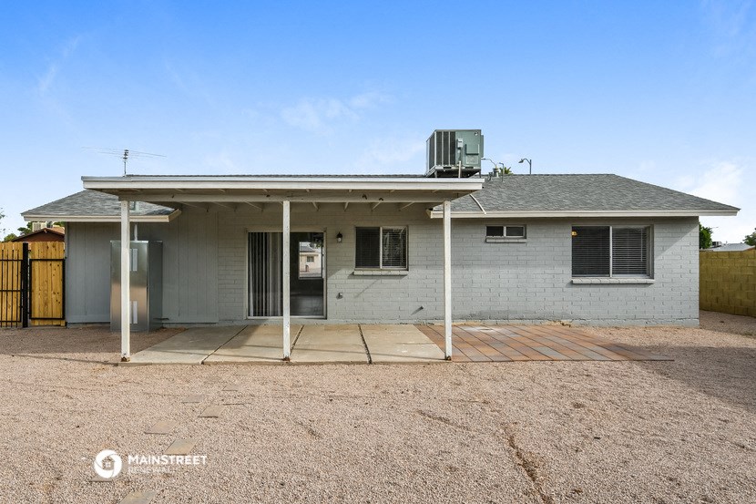 a small white house with a dirt yard and a gate
