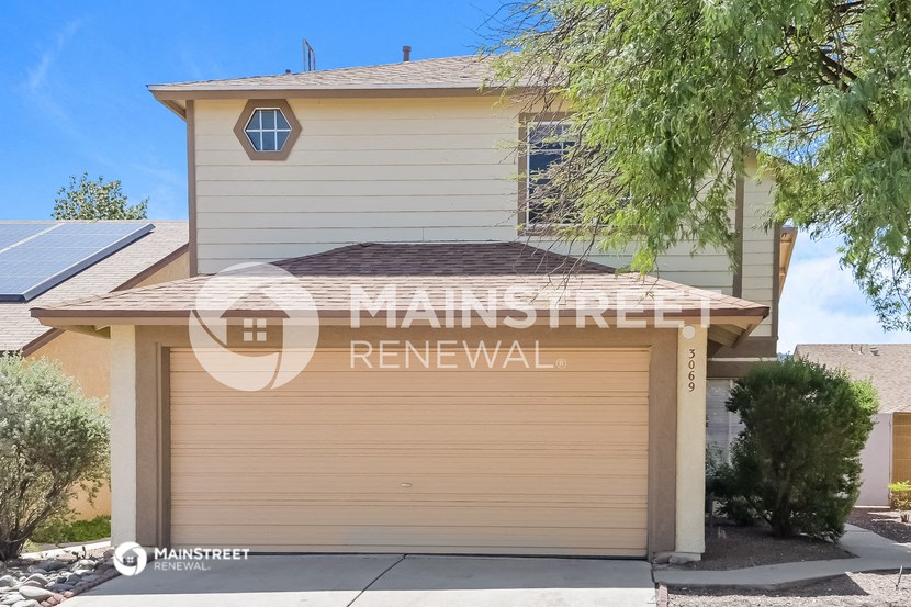 a home with a garage and a tree in front of it