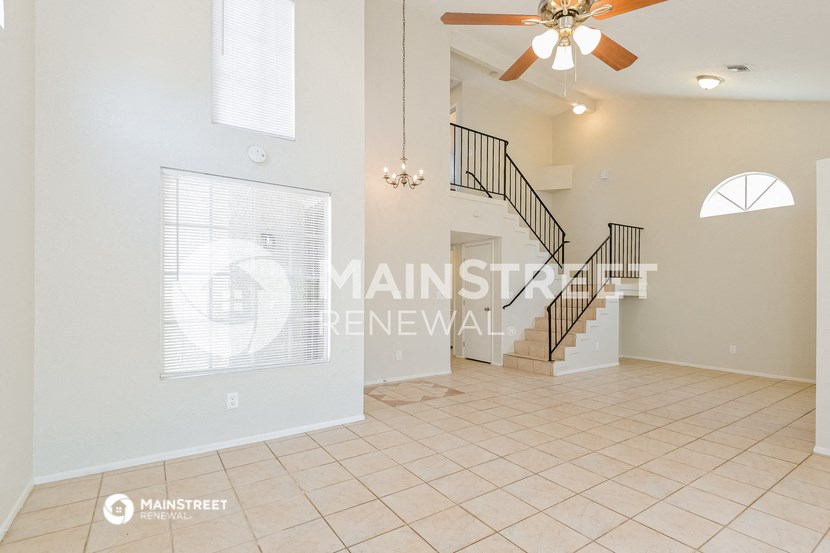 a large living room with a staircase and a ceiling fan