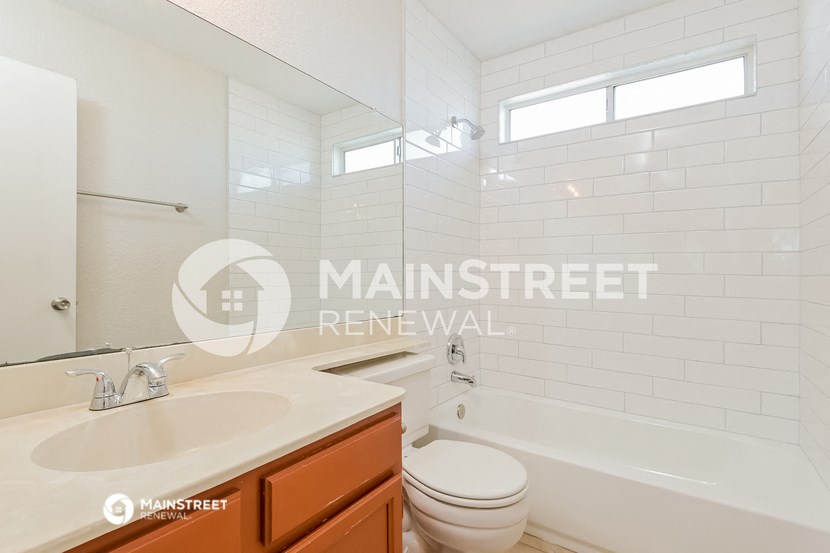 bathroom with white subway tiles and a sink and toilet