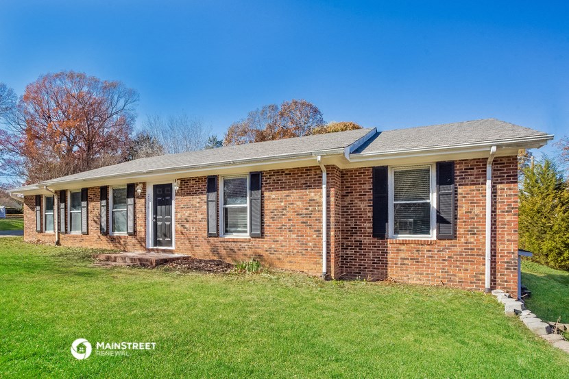 a brick house with a green lawn and a blue sky