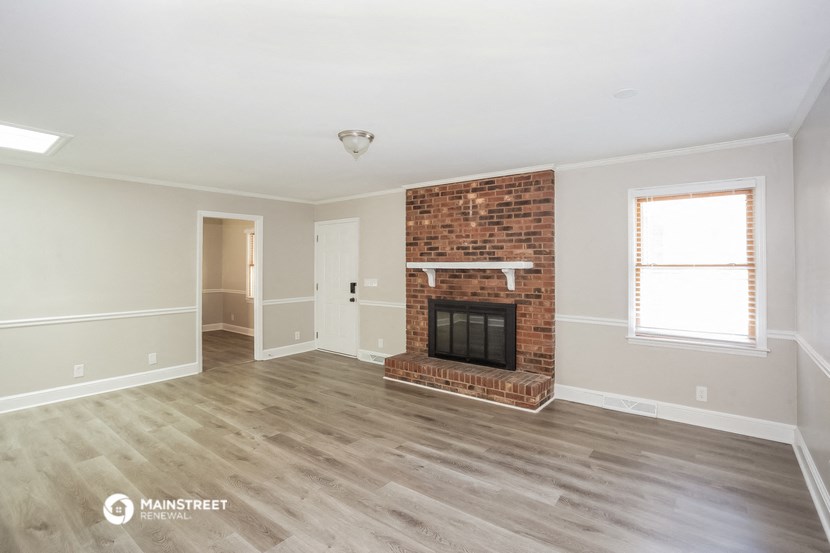 the living room has a brick fireplace and hardwood floors