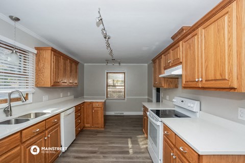 a kitchen with wooden cabinets and white counters and appliances