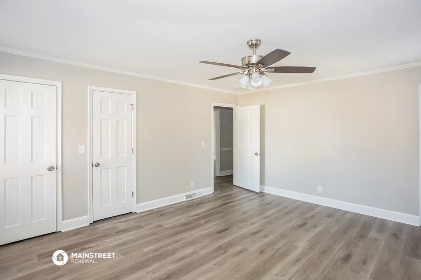 a living room with white walls and a ceiling fan