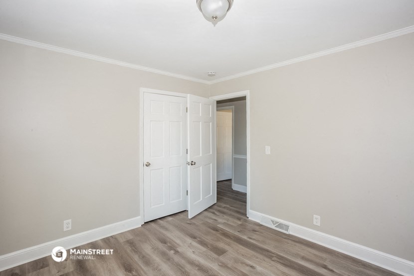 a bedroom with white walls and white doors and a door to a closet