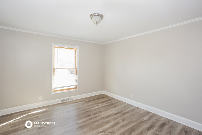 an empty room with wood floors and a window