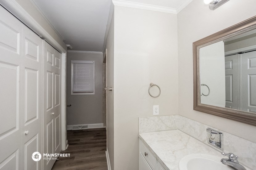 a bathroom with a sink and a mirror and a door to a closet