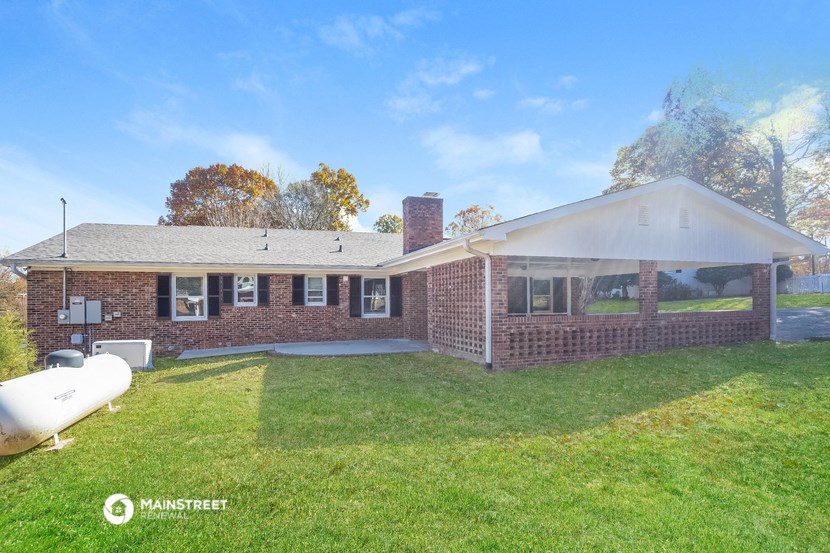 a brick house with a lawn and a boat in the yard