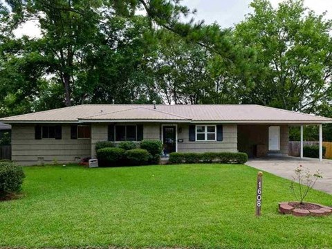 A house with a brown roof and a green lawn.