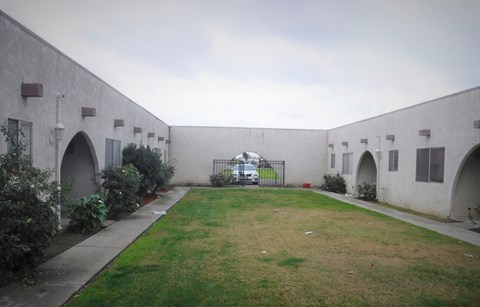 a yard in front of a white building with a gate