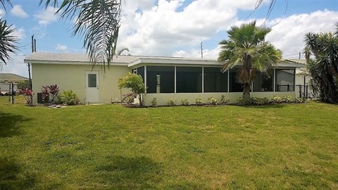 a house with a lawn and palm trees in front of it