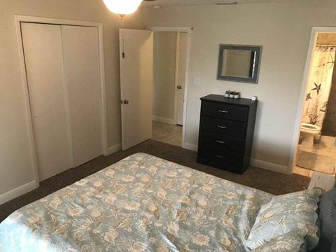a bedroom with a bed and a dresser and a bathroom