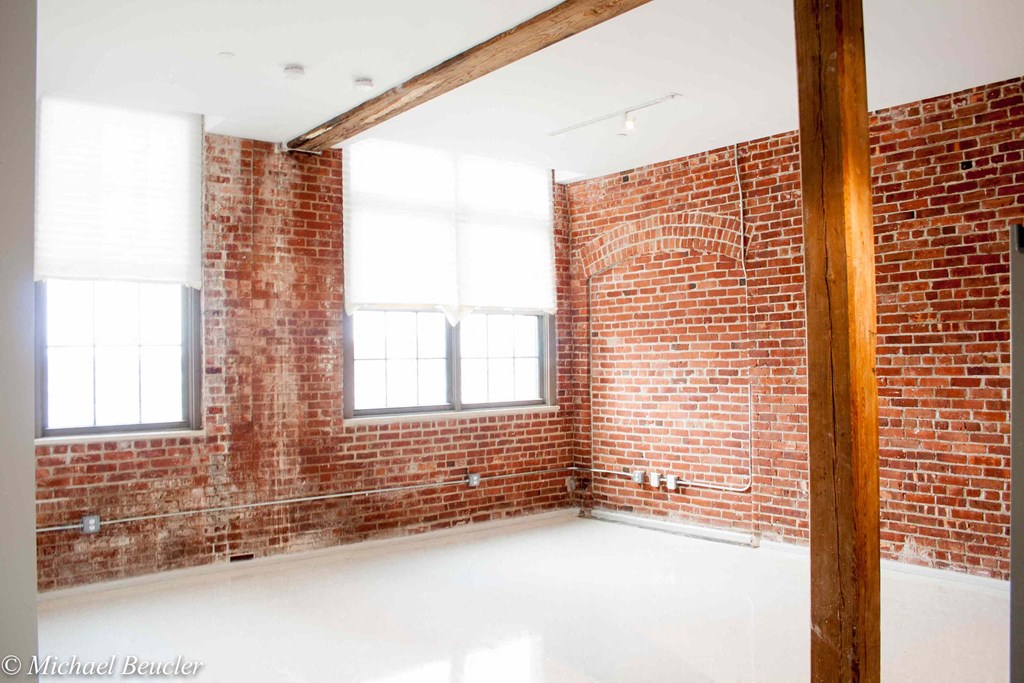 an empty room with a brick wall and a large window