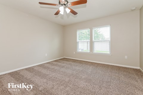 the spacious living room with ceiling fan and carpeting