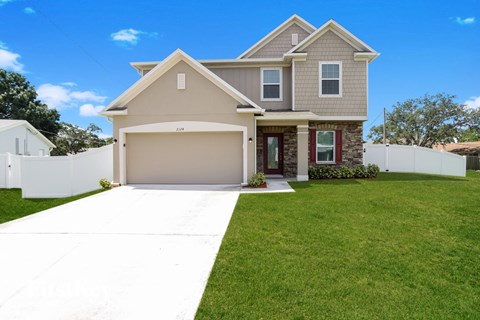a beige house with a garage door and a lawn