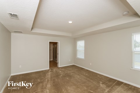 the spacious living room with white walls and tile flooring