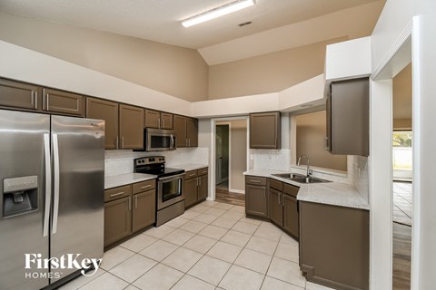 A kitchen with a refrigerator, oven, microwave, and sink.