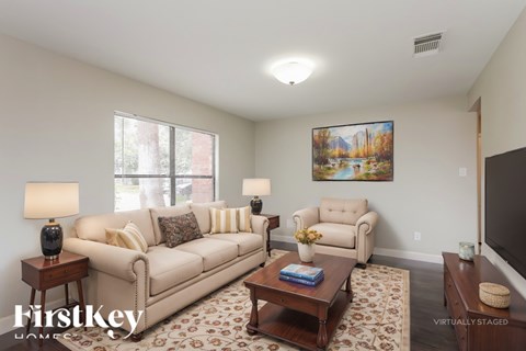 A living room with a beige couch, a coffee table, and a painting on the wall.