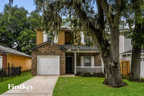 a brick house with a white garage door and a large tree