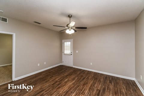 the spacious living room with hardwood flooring and a ceiling fan