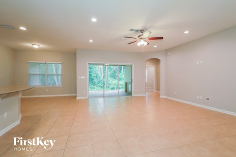 A spacious room with a ceiling fan and sliding glass doors leading to a garden.