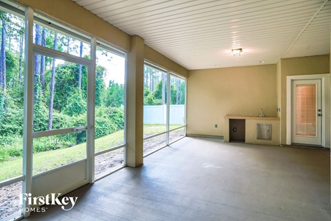 A large empty room with a view of trees outside through the windows.