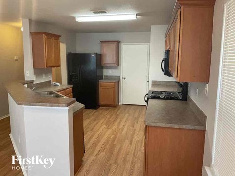 A kitchen with wooden cabinets and a black refrigerator.