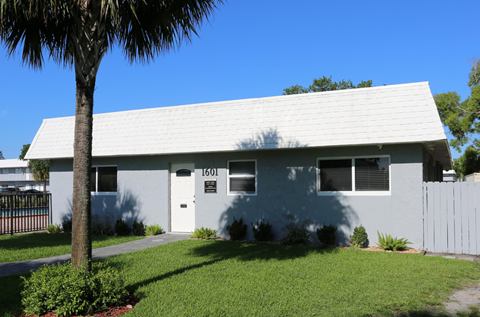the front of a white house with a white roof and a palm tree
