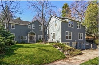a blue house with a green lawn and a sidewalk