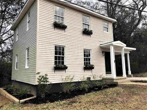 A two-story house with a porch and flower boxes on the windows.