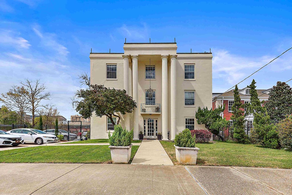 the front of a building with columns and a sidewalk