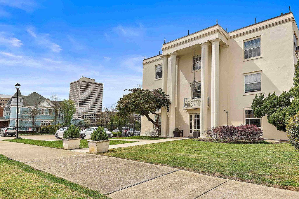 an apartment building with a sidewalk and lawn in front of it