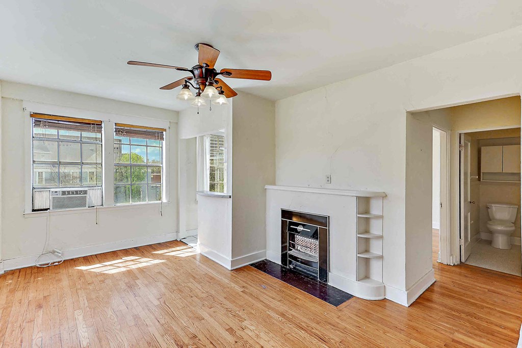 an empty living room with a fireplace and a ceiling fan