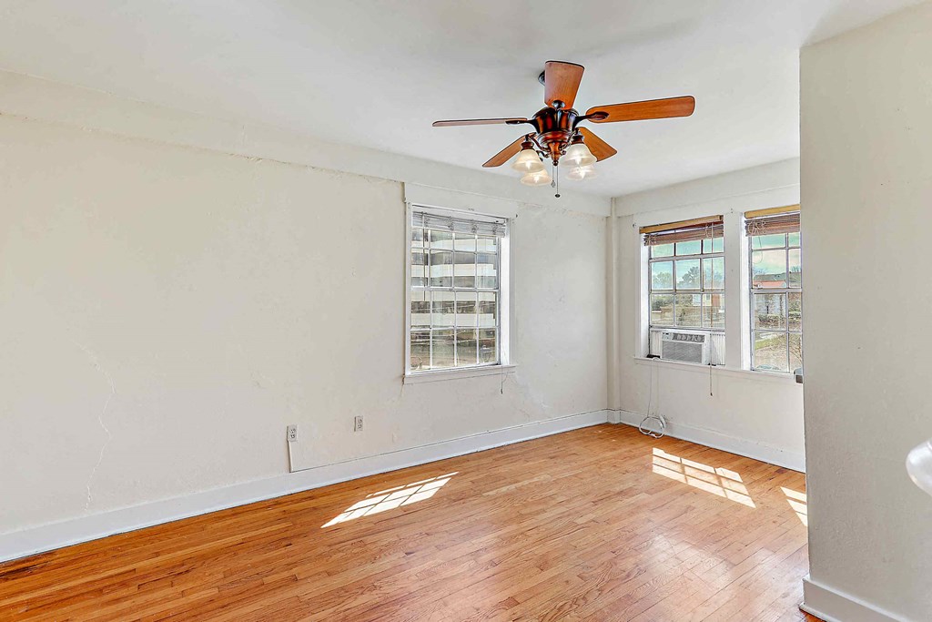 an empty living room with a ceiling fan and a window