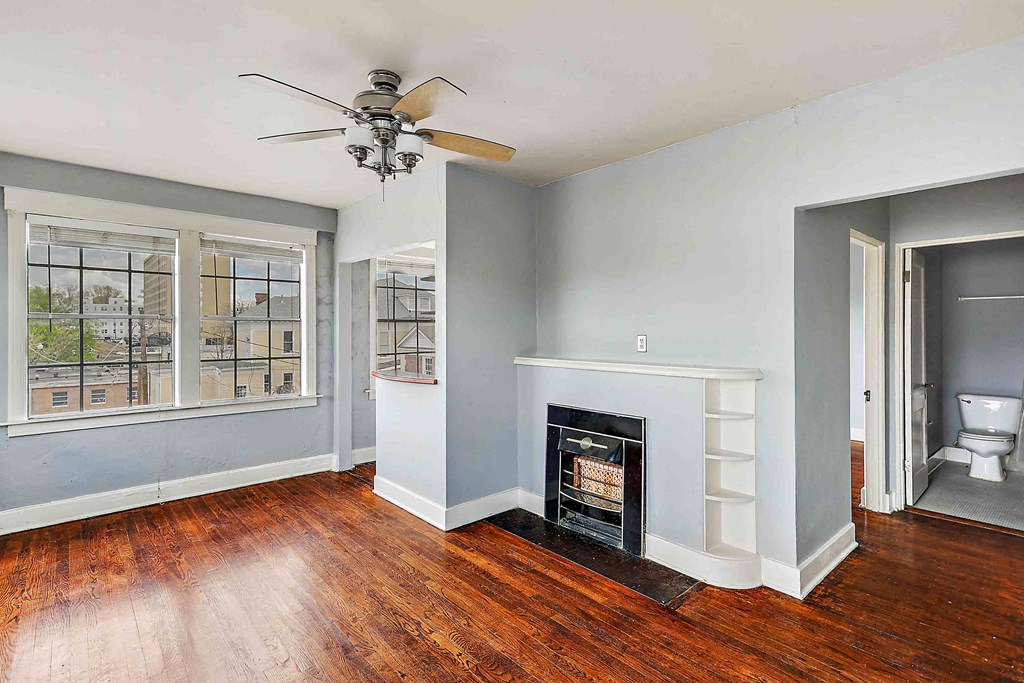 an empty living room with a fireplace and a ceiling fan