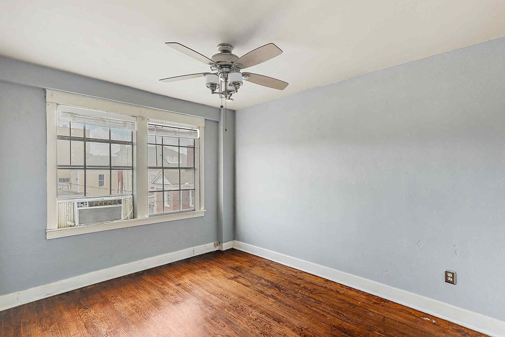 an empty room with a ceiling fan and a window