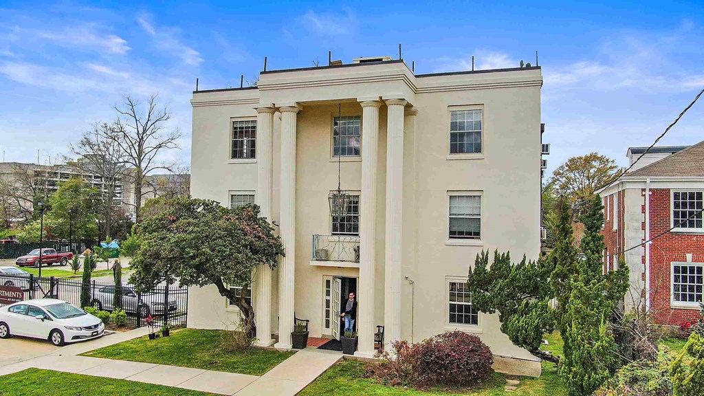 a man standing in front of a white building with columns