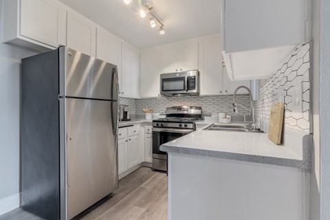 a kitchen with white cabinets and stainless steel appliances