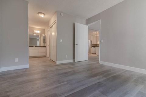 a spacious living room with white walls and wood floors