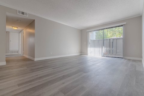 the living room and dining room of an empty house with a large window