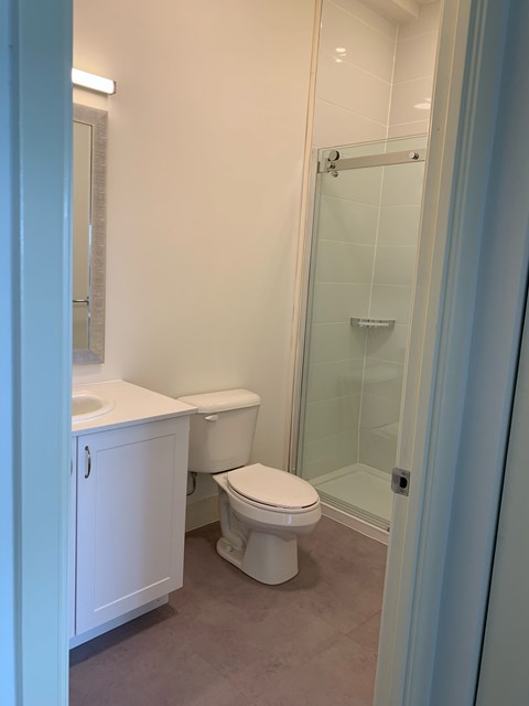 A white toilet sits in a bathroom next to a walk-in shower.
