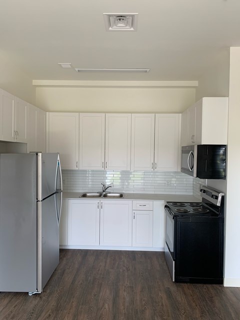 A kitchen with white cabinets and a black stove.