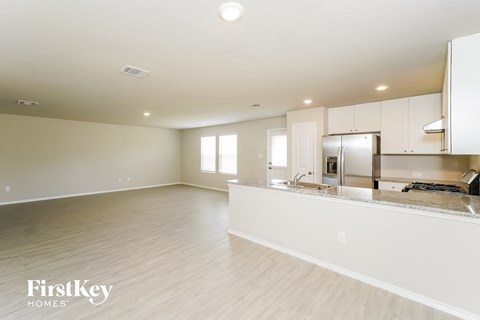 A spacious kitchen with white cabinets and a marble countertop.